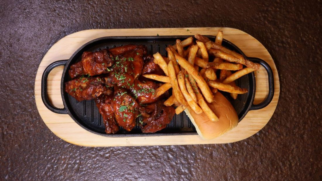 Glazed chicken wings with fries and a bun