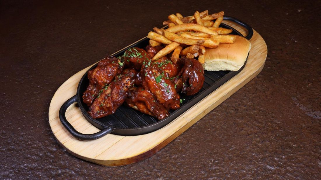 Glazed chicken wings with fries and a bun