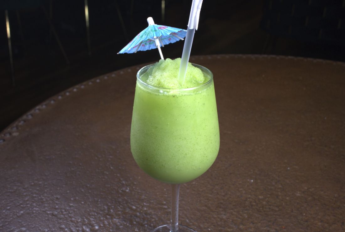 Green slushy drink with a cocktail umbrella