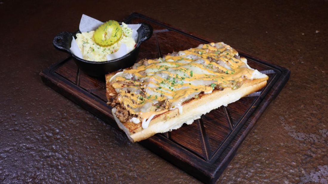 Cheesesteak-style sandwich on toasted bread with a side